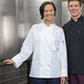 A man and woman wearing Uncommon Chef white chef coats with a mesh back.