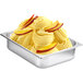 A bowl of yellow ice cream with slices of mango on a counter.
