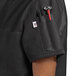 A black Uncommon Chef short sleeve chef coat with red accents on the pocket worn by a person.