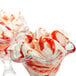A glass bowl of ice cream with Fabbri strawberry marbling and white sprinkles.