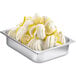 A metal container of whipped cream with lemons on a white surface.