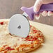 A person using a Choice 4" pizza cutter with a purple handle to slice a cheese pizza.