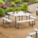A Lancaster Table & Seating white picnic table with attached benches on a stone path.