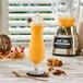 A glass of pumpkin spice soft serve with whipped cream and spices with a star anise on top sitting on a table with a blender.