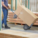 A person in blue jeans pushing a Lavex 2-in-1 hand truck with a box.