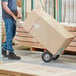 A man using a Lavex hand truck to move a large box.
