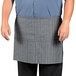 A man wearing a grey Uncommon Chef waist apron with pockets.