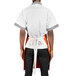 A man wearing an orange and white Uncommon Chef apron with natural webbing.