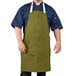 A man wearing a moss green Uncommon Chef bib apron with natural webbing.
