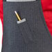 A person wearing a black denim apron with a pencil in the pocket.