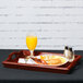 A mahogany hardwood room service tray holding a plate of food and a glass of orange juice.
