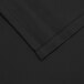 A close-up of a black fabric square with a hemmed edge.