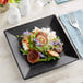 A matte black Acopa stoneware plate with food on it.