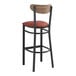 A Lancaster Table & Seating bar stool with a burgundy vinyl seat and vintage wood back on a black frame.