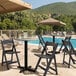 A black Lancaster Table & Seating folding chair next to a pool.