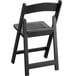 A black Lancaster Table & Seating folding chair with a slatted seat.