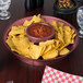 A Raspberry Polypropylene round deli server filled with salsa and chips on a table.
