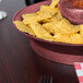 A bowl of chips and salsa in a HS Inc. raspberry round deli server on a table.