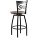 A Lancaster Table & Seating black cross back swivel bar stool with a vintage wood seat.