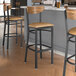 Lancaster Table & Seating Boomerang Series bar stools with light brown vinyl seats and vintage wood backs at a restaurant counter.