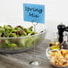 An American Metalcraft stainless steel table card holder holding a sign in a bowl of salad