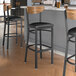 A group of Lancaster Table & Seating Boomerang Series bar stools with black vinyl seats and vintage wood backs.