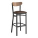 A Lancaster Table & Seating black bar stool with dark brown vinyl seat and vintage wood back.