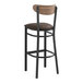 A Lancaster Table & Seating black metal bar stool with a wood back and dark brown cushion.