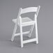A white Lancaster Table & Seating folding chair with a slatted seat.
