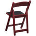 A mahogany Lancaster Table & Seating folding chair with black vinyl seat.