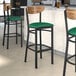 A Lancaster Table & Seating Boomerang Series bar stool with a green vinyl seat.