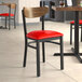 A Lancaster Table & Seating Boomerang Series chair with a red vinyl seat and a black wood back.