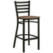 A Lancaster Table & Seating black finish bar stool with a vintage wood seat.