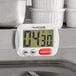 An AvaTime white digital kitchen timer with black numbers on a kitchen counter.