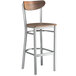 A Lancaster Table & Seating Boomerang bar stool with a vintage wood seat and back and metal frame.