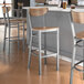 A Lancaster Table & Seating bar stool with a wooden seat and back and metal legs.
