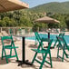 A Lancaster Table & Seating green folding chair on a table by a pool.