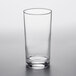 An Arcoroc ArcoPrime beverage glass filled with a clear beverage and a straw on a white surface.
