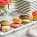 A tray of White Toque French Signature assorted macarons on a table in a bakery display.