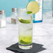 A Stolzle tall tumbler with a drink and lime wedge on a napkin.