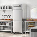 A stainless steel kitchen with a large Avantco reach-in refrigerator.