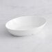 A white oval bowl on a marble surface.