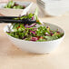 A Tablecraft white melamine oval bowl filled with salad.