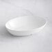 A white Tablecraft Sierra oval melamine bowl on a marble surface.