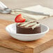 A Tablecraft white mini melamine plate with a chocolate cake and a strawberry on it.