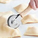 A hand using a Fox Run stainless steel pastry crimper with a wood handle to cut dough.