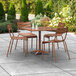 A Lancaster Table & Seating brown powder-coated aluminum outdoor dining table with chairs on a patio.