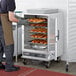 A man using a ServIt holding and proofing cabinet to warm trays of pastries.