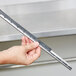 A hand holding a metal bar with a blade on the end.
