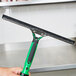 A hand holding a green and black Unger squeegee blade.